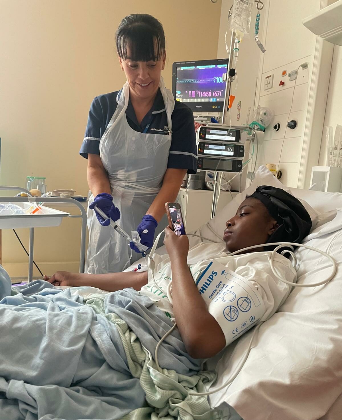 Nurse giving treatment to patient laying in bed.