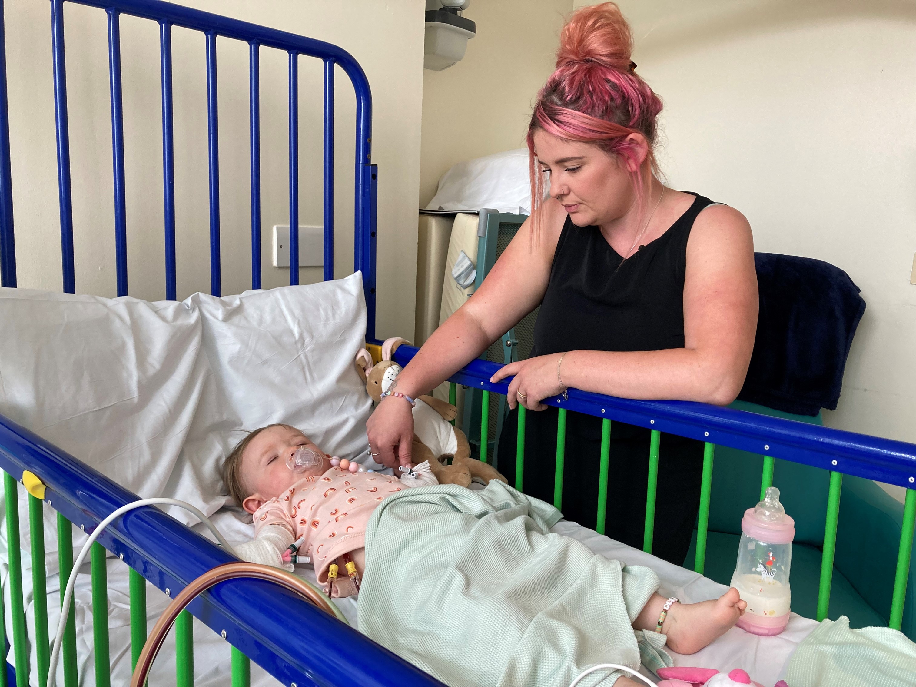 Photo of Teddi lying in a hospital bed next to her mother