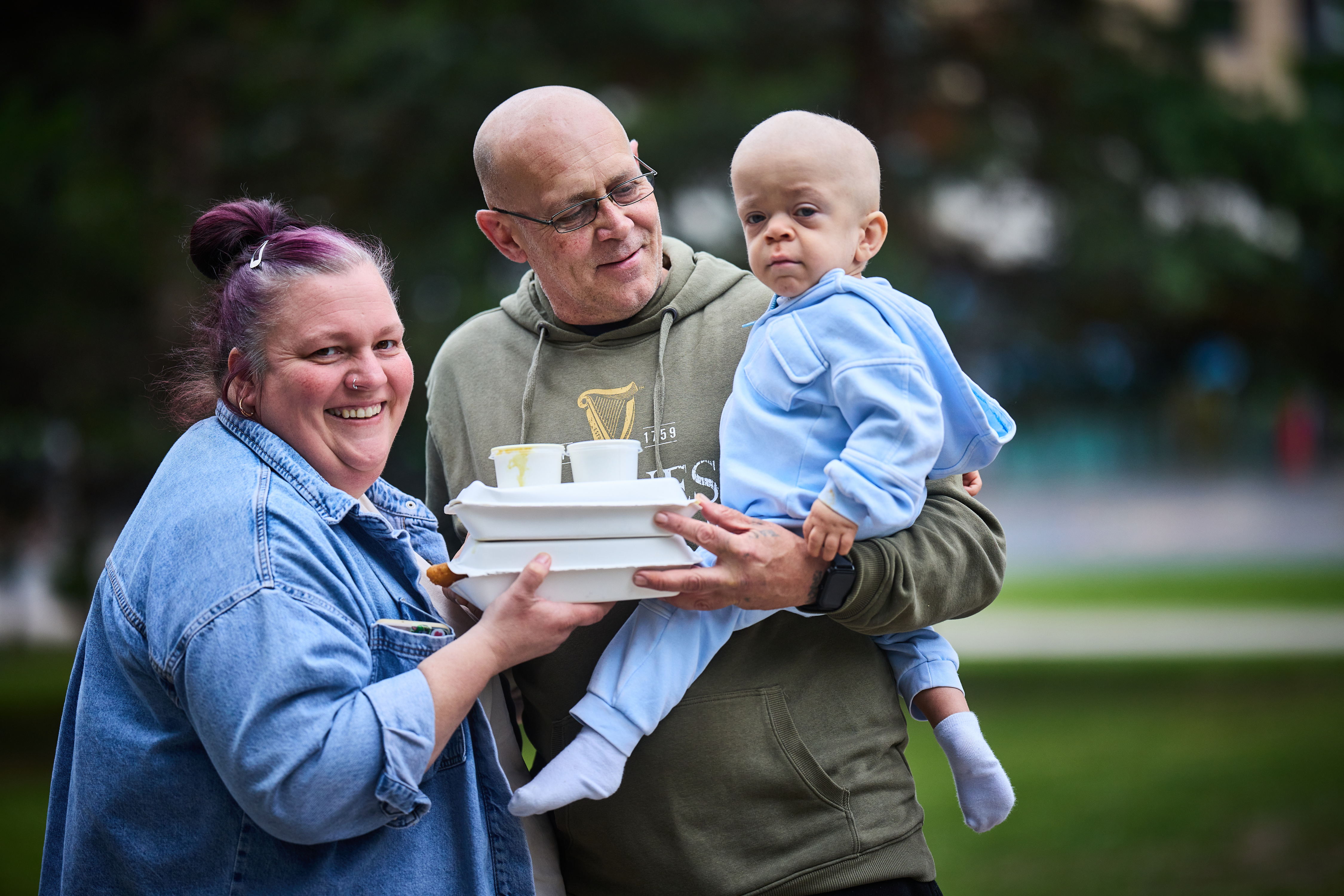 A man and a woman holding their child and takeaway boxes