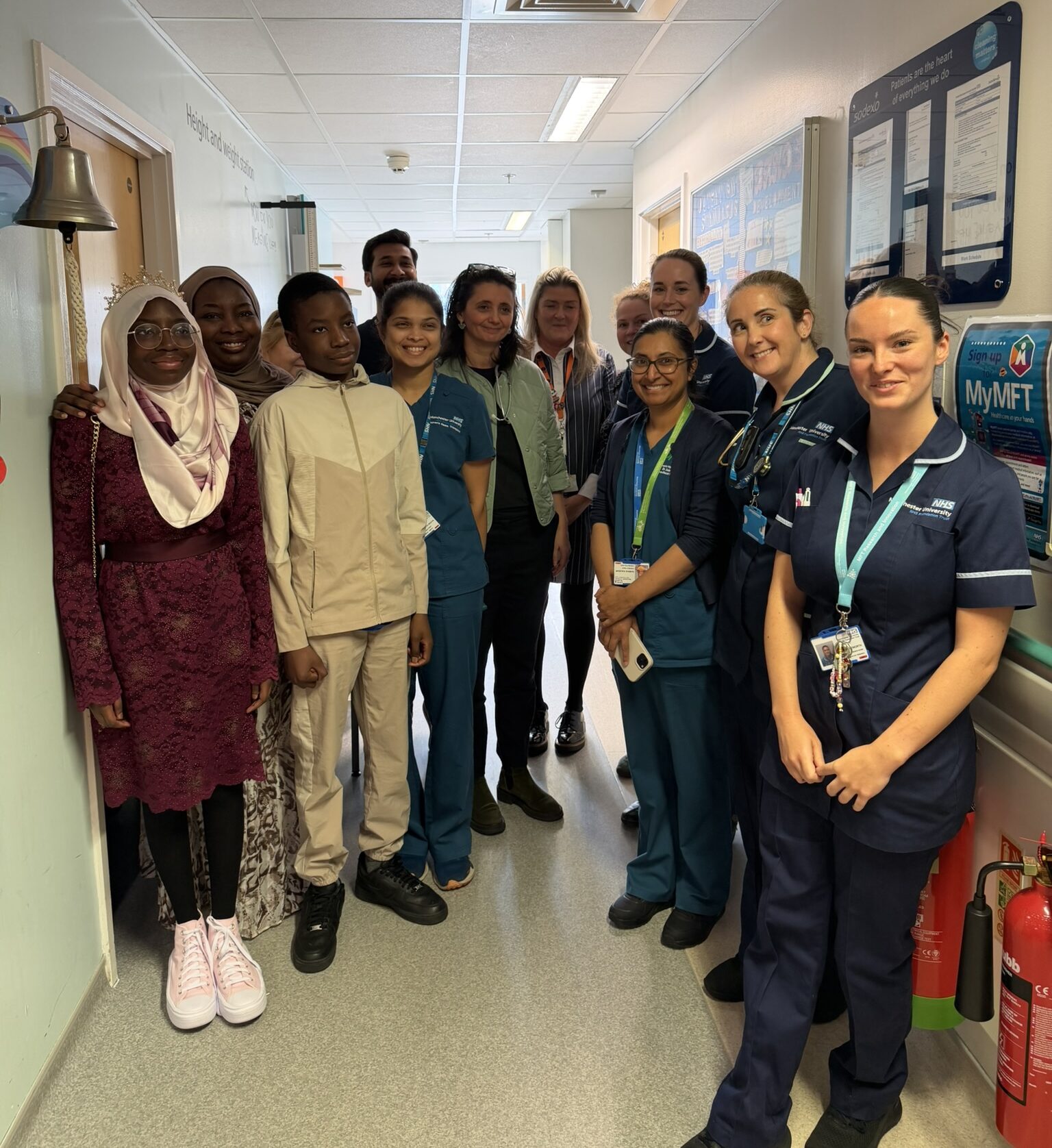 Group of people stood in hospital corridor.